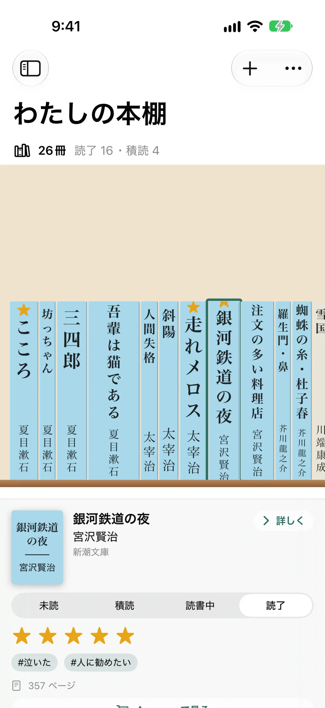 「わたしの本棚」の画面。26冊・読了16・積読4。こころ・坊っちゃん・三四郎・吾輩は猫である・人間失格・走れメロス・銀河鉄道の夜などの背表紙が縦書きで並び、★5の本には星の印。下に選んだ本「銀河鉄道の夜」の情報（読了・★5つ・#泣いた・#人に勧めたい）